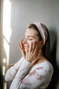“Woman applying skincare cream on face for dry skin hydration routine
